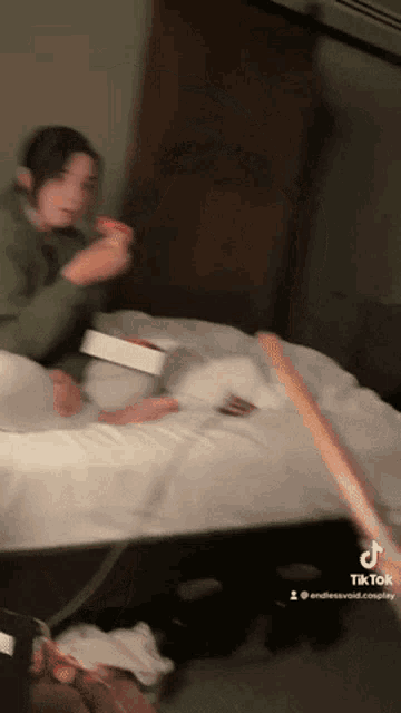 a woman is sitting on a bed eating a pizza and a tik tok video is being played