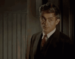 a man in a suit and tie is standing in front of a wall .