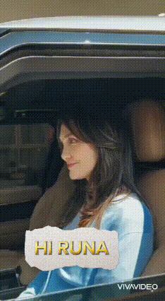 a woman is sitting in the driver 's seat of a car with a sign that says hi runa on it