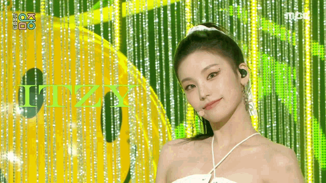 a woman stands in front of a yellow and green background with the letters itzy