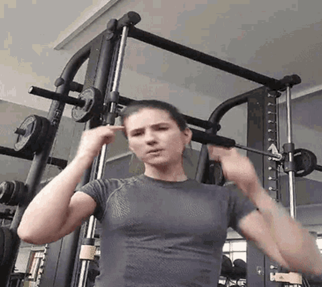 a woman is standing in front of a barbell in a gym .