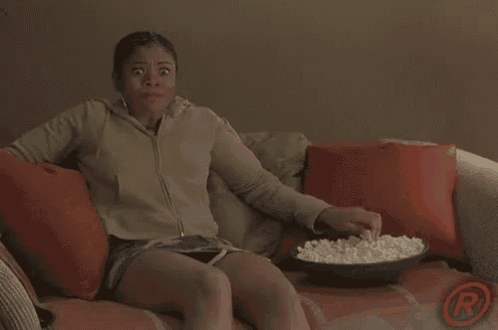 a woman sitting on a couch with a bowl of popcorn