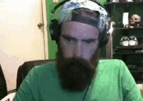 a man with a beard and headphones is wearing a green shirt .