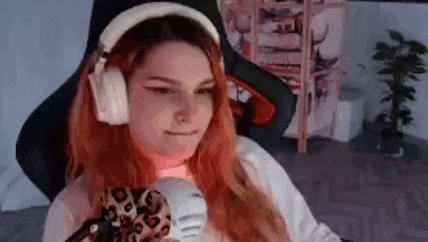 a woman with red hair is wearing headphones and holding a stuffed animal in her hand .