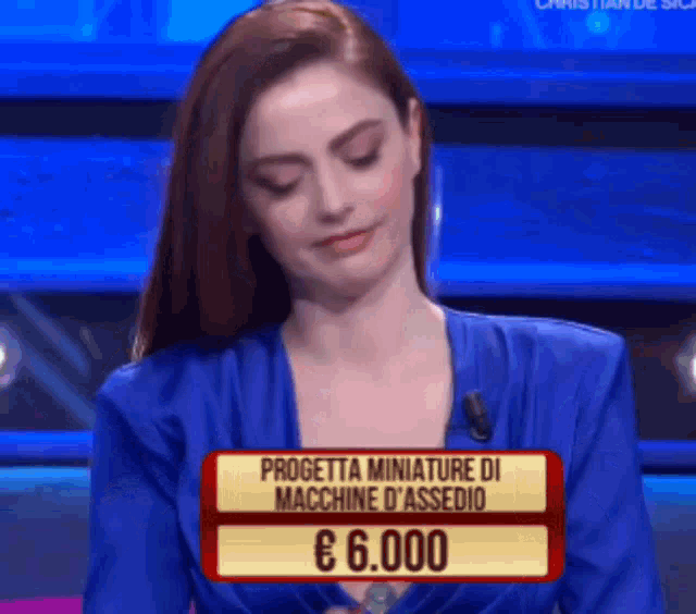 a woman in a blue dress is sitting in front of a sign that says progetta miniature di macchine d' assed