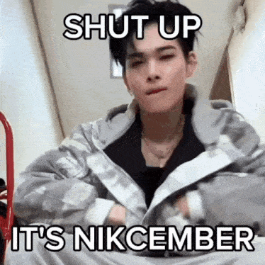a man wearing a jacket with the words shut up it 's nikcember written on it .