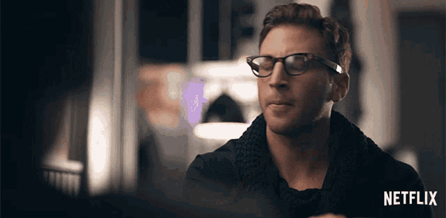 a man wearing glasses and a scarf has a netflix logo in the corner