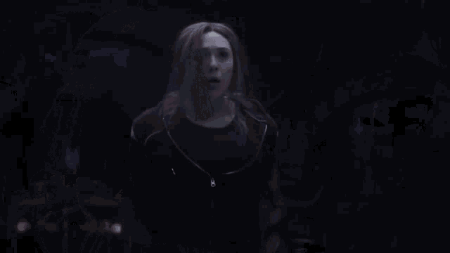 a person is flying through the air in a dark room while a woman stands in the background .