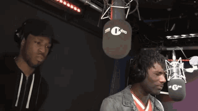 a man wearing headphones stands in front of a microphone that says bbc 1