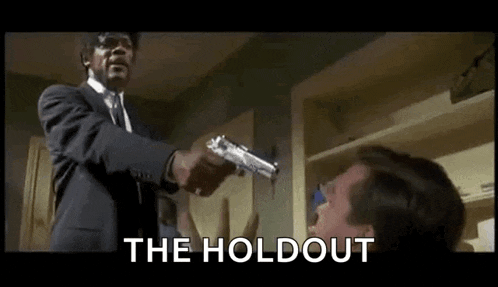 a man in a suit and tie is holding a gun to another man .