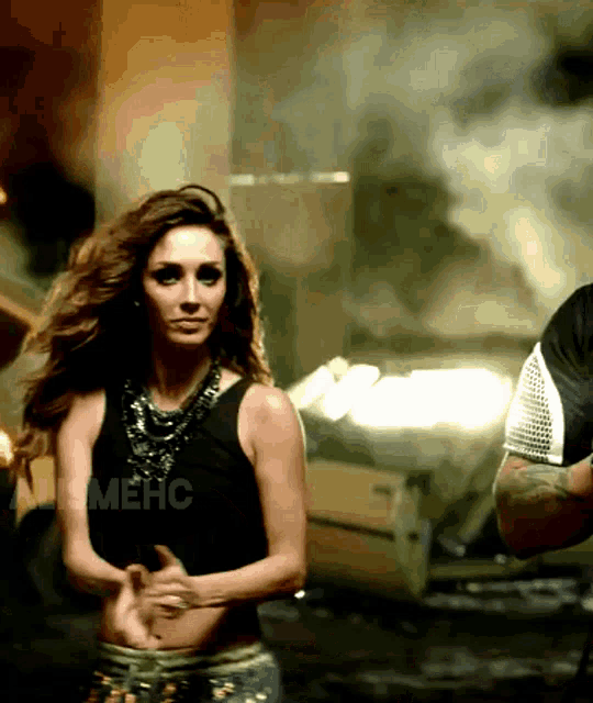 a woman in a black tank top is dancing next to a man in a black shirt with the word mehc on it