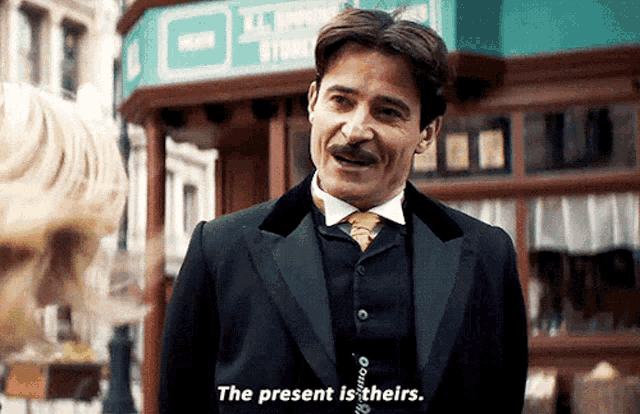 a man in a suit says the present is theirs in front of a store