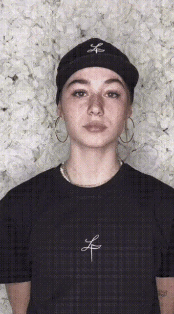 a woman wearing a black t-shirt with the letter l on the front