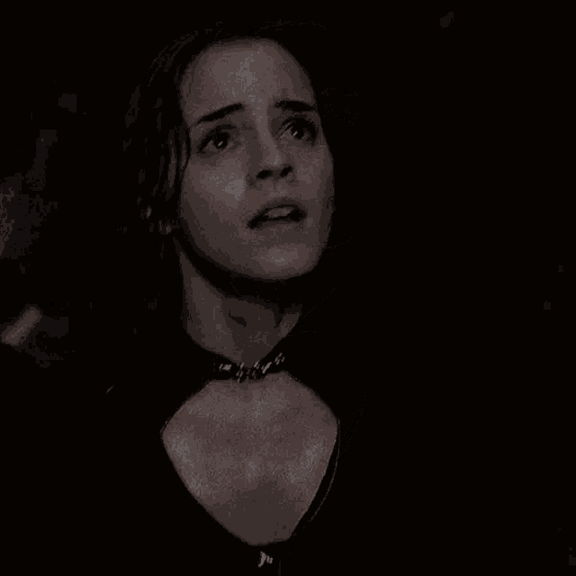 a close up of a woman 's face in a dark room with a choker around her neck .
