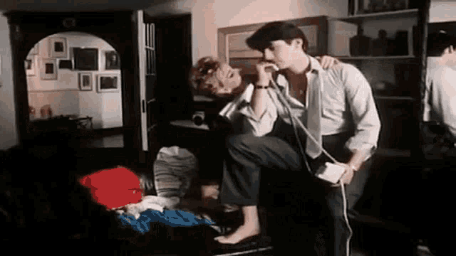 a man is carrying a woman in his arms while talking on a phone .