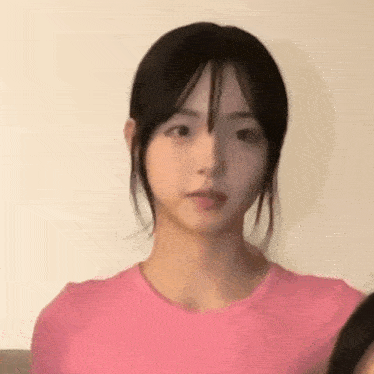 a close up of a girl wearing a pink shirt .
