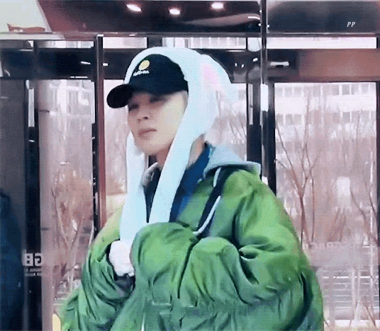 a person wearing a green jacket and a black hat with a bunny ear on it .