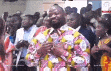 a man in a colorful shirt is standing in front of a crowd of people .