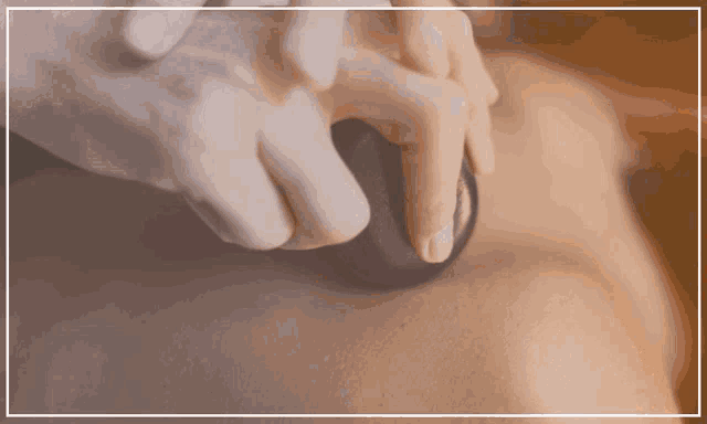 a person is getting a massage with a black stone