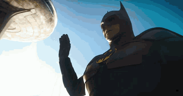 a man in a batman costume is standing in front of a blue sky