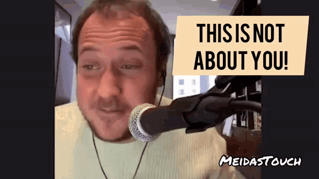 a man talking into a microphone with a sign that says " this is not about you "