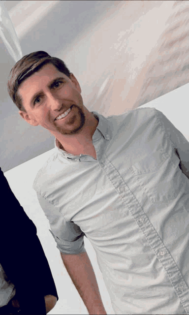 a man with a beard is wearing a white shirt and smiling