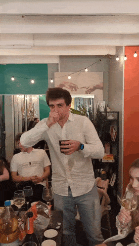 a man in a white shirt is holding a cup in his hand