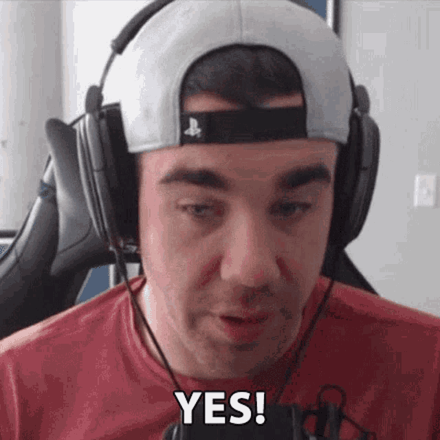 a man wearing headphones and a hat is making a funny face and saying yes .