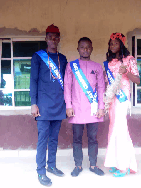 a man in a purple shirt has a sash on his chest that says ' nigerian ' on it