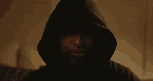 a man wearing a hooded jacket is smiling in the dark .
