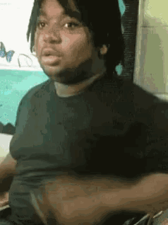 a man with dreadlocks is wearing a black shirt and making a funny face