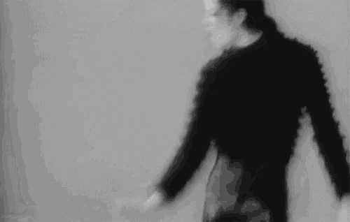 a blurry black and white photo of a man in a black sweater dancing .
