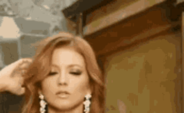 a woman with red hair and earrings is getting her hair done by a hairdresser .