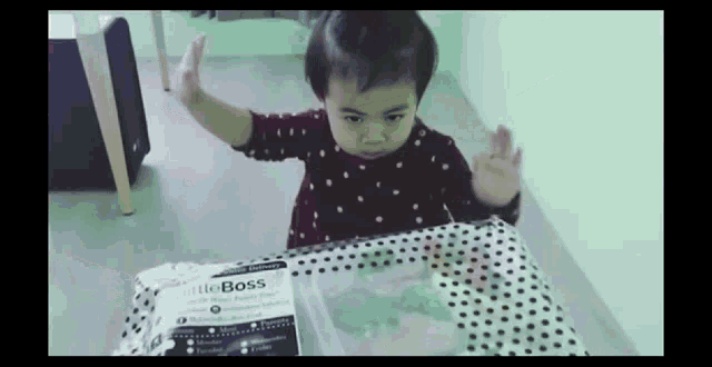 a little girl is standing in front of a package that says little boss