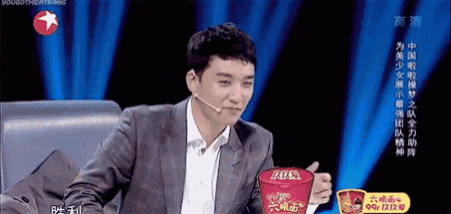 a man in a suit is holding a cup of ramen