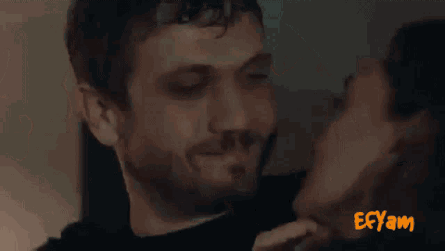 a man and a woman are kissing in front of a sign that says " eeyam "