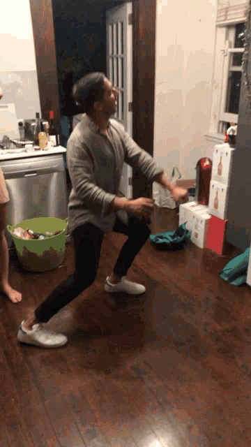 a man dancing in a kitchen with boxes of toilet paper stacked on the floor