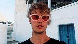 a young man wearing pink sunglasses is standing in front of a building
