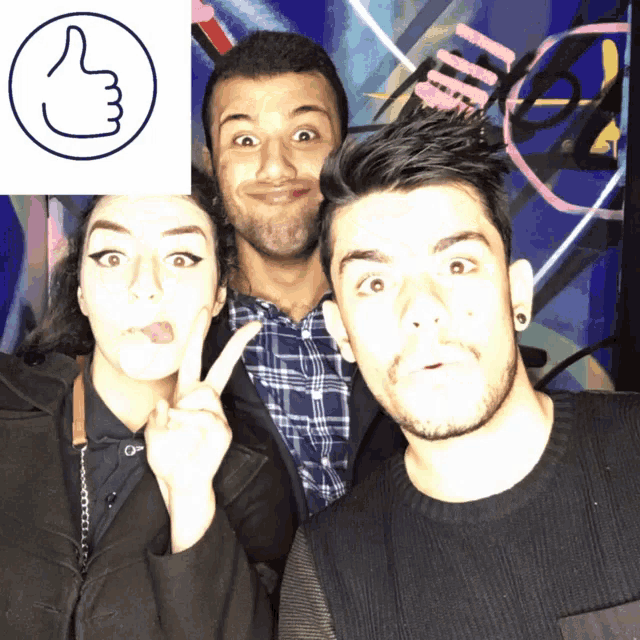 three people posing for a picture with a thumbs up symbol