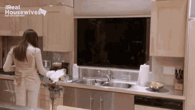 a woman standing in a kitchen with the words real housewives out of context on the bottom