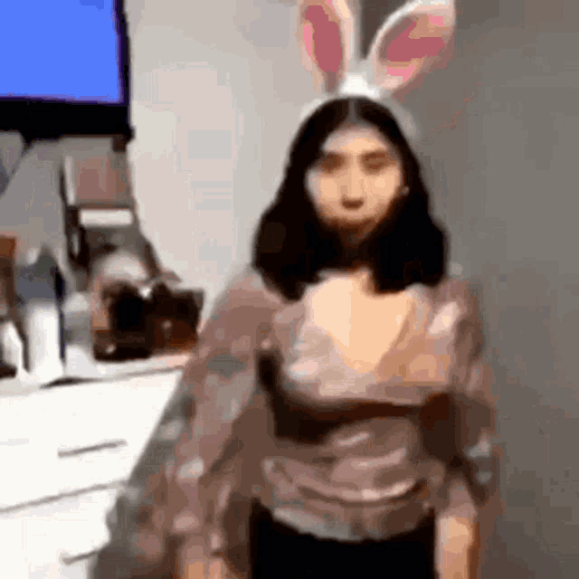 a woman is wearing bunny ears and standing in front of a television .