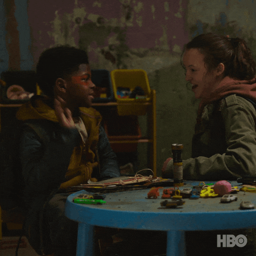 a woman and a boy are sitting at a table with a hbo logo in the corner