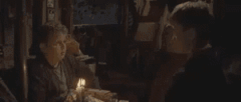 a man is sitting at a table with a candle and the words " you 're killing me smalls "