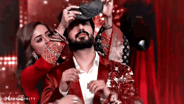 a woman is putting a hat on a man 's head while another woman looks on ..