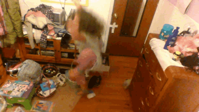 a girl is jumping in the air in a messy room with a bottle of shampoo on the dresser