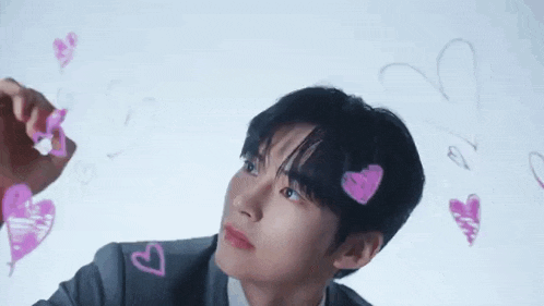 a man in a suit and tie is drawing hearts with a marker .