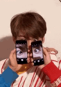 a man is holding two phones in front of his face .