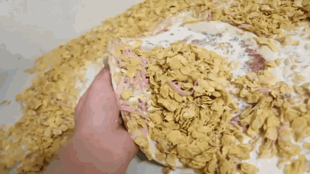 a person is holding a tortilla over a pile of cereal .