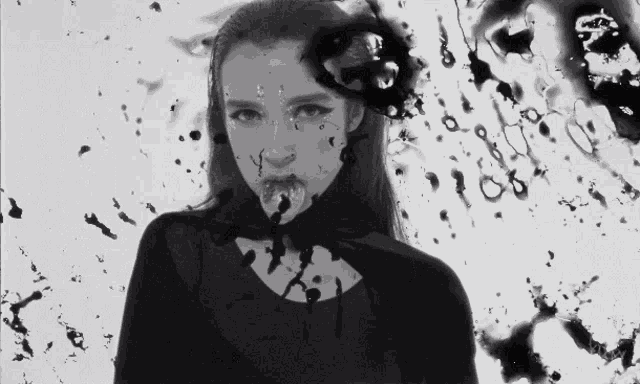 a black and white photo of a woman with ink splashing on her face