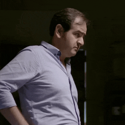 a man in a blue shirt and tie is standing with his hands on his hips